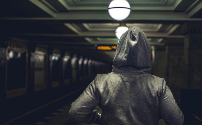 person wearing gray hooded jacket in train station